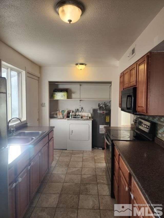 kitchen with black microwave, washing machine and dryer, electric water heater, range with electric stovetop, and a sink