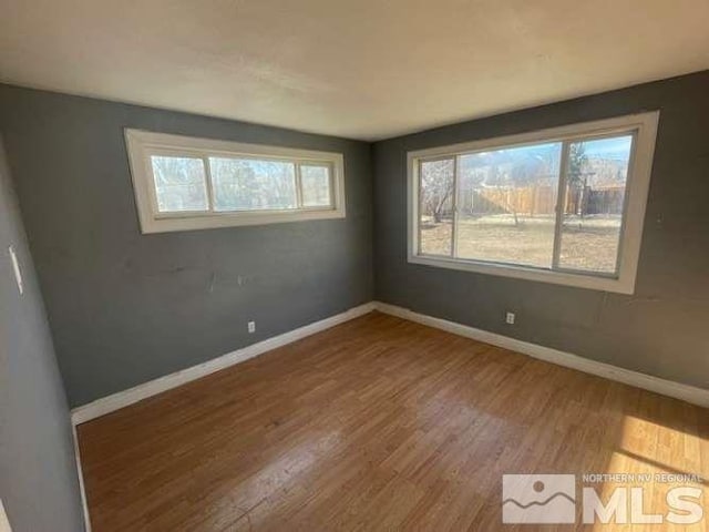 unfurnished room with baseboards and wood finished floors