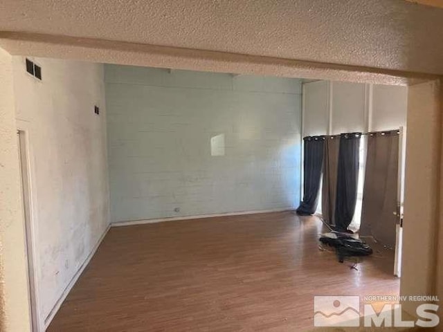 unfurnished living room with visible vents, beamed ceiling, a textured ceiling, and wood finished floors