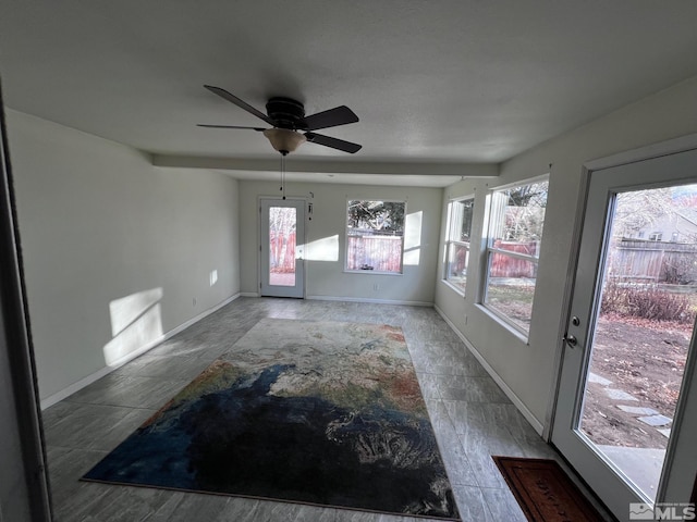 unfurnished sunroom featuring ceiling fan