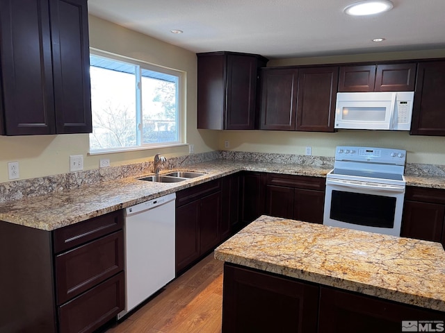 kitchen featuring dark brown cabinets, light hardwood / wood-style floors, white appliances, and sink