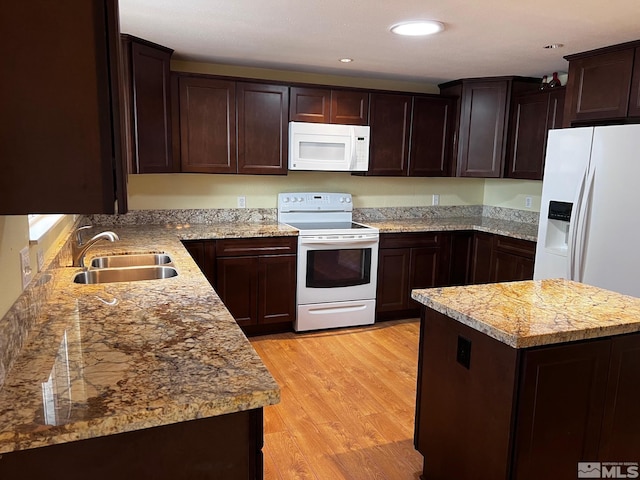 kitchen with white appliances, sink, light stone countertops, light wood-type flooring, and dark brown cabinets