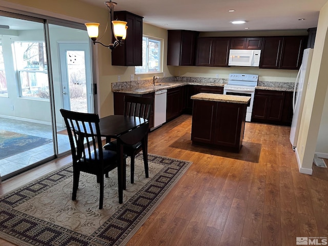 kitchen featuring a center island, white appliances, light hardwood / wood-style flooring, decorative light fixtures, and a chandelier