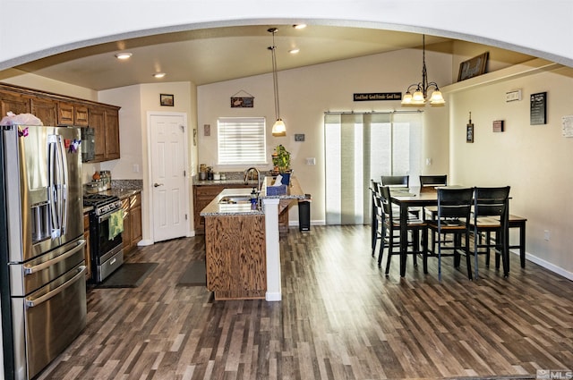 kitchen with light stone counters, hanging light fixtures, vaulted ceiling, and appliances with stainless steel finishes