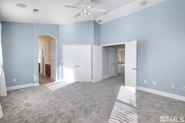 unfurnished bedroom featuring connected bathroom, light colored carpet, high vaulted ceiling, and ceiling fan