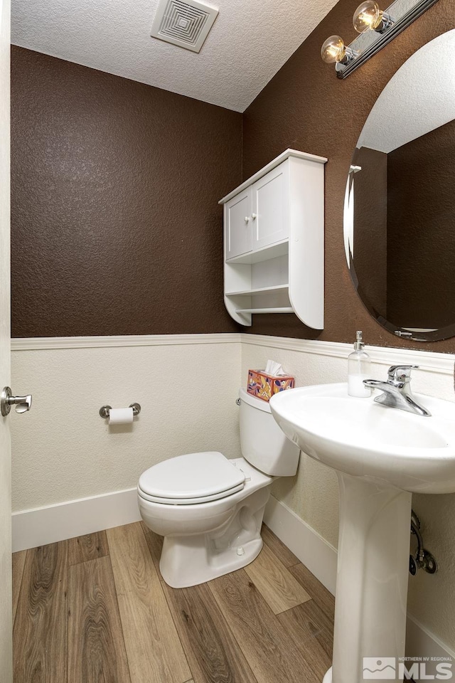 bathroom featuring wood-type flooring, a textured ceiling, and toilet