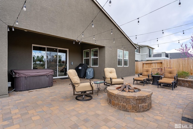 view of patio / terrace featuring a fire pit, area for grilling, and a hot tub