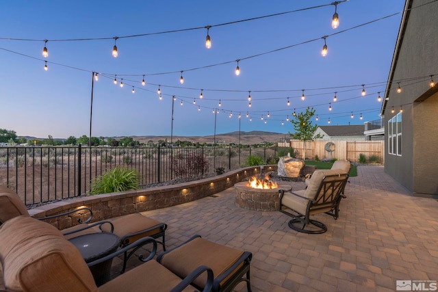 patio terrace at dusk with a mountain view and an outdoor living space with a fire pit