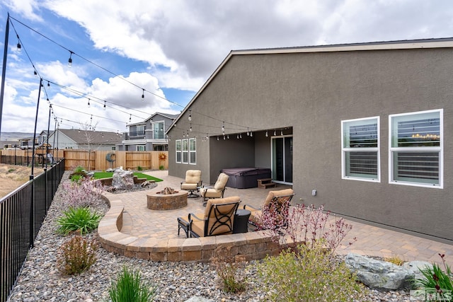 rear view of property with a patio, a hot tub, and an outdoor fire pit