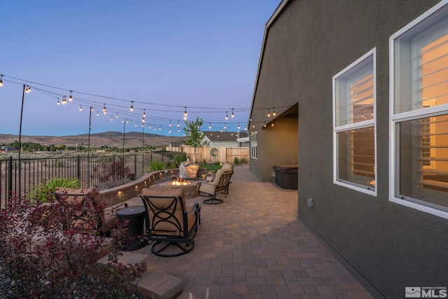 patio terrace at dusk featuring a mountain view and an outdoor fire pit