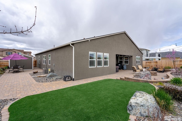 back of property featuring a patio area, a yard, and an outdoor fire pit