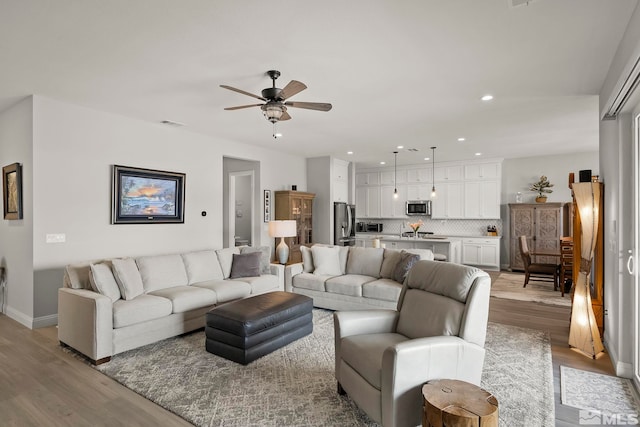 living room with ceiling fan and light hardwood / wood-style flooring