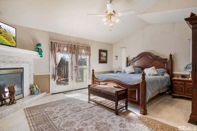 bedroom featuring access to exterior, ceiling fan, a high end fireplace, light colored carpet, and vaulted ceiling