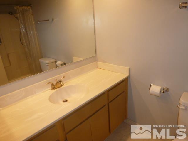 bathroom with a shower with shower curtain, tile patterned floors, vanity, and toilet