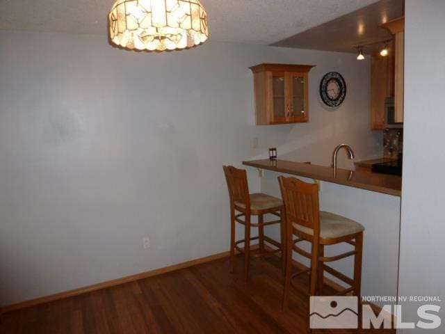 kitchen featuring a kitchen breakfast bar, dark hardwood / wood-style flooring, kitchen peninsula, and sink