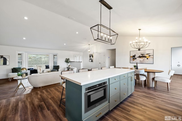 kitchen with a kitchen bar, dark wood-type flooring, a notable chandelier, a kitchen island, and hanging light fixtures