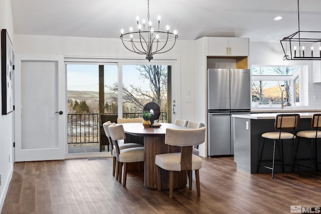 dining room with sink, dark hardwood / wood-style flooring, and a notable chandelier