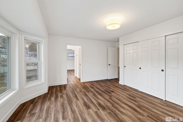 unfurnished bedroom with dark hardwood / wood-style flooring and a closet