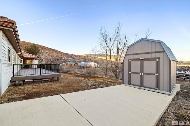 view of patio / terrace with a storage shed and a deck with mountain view