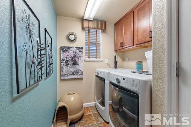 clothes washing area featuring cabinets, a textured ceiling, and washer and clothes dryer