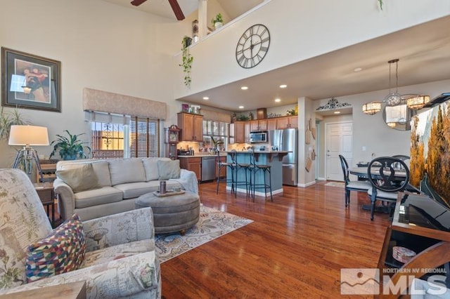 living room with high vaulted ceiling, dark hardwood / wood-style floors, and ceiling fan with notable chandelier