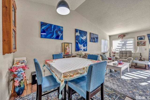 dining area featuring hardwood / wood-style floors, a textured ceiling, and vaulted ceiling