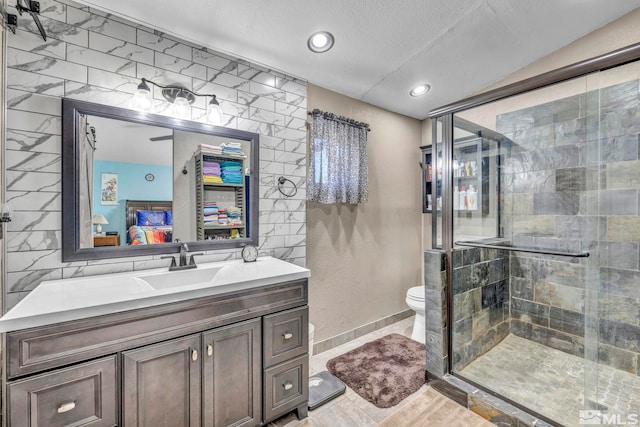 bathroom featuring vanity, a textured ceiling, toilet, and an enclosed shower