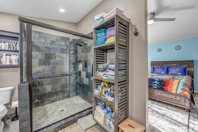 bathroom with ceiling fan, a shower with door, vaulted ceiling, and toilet