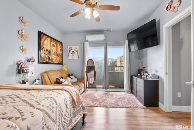 bedroom featuring hardwood / wood-style floors, a wall unit AC, and ceiling fan