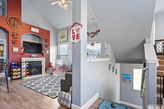 living room featuring ceiling fan, high vaulted ceiling, and light hardwood / wood-style floors