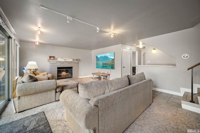 living room with tile patterned floors, a fireplace, rail lighting, and a textured ceiling