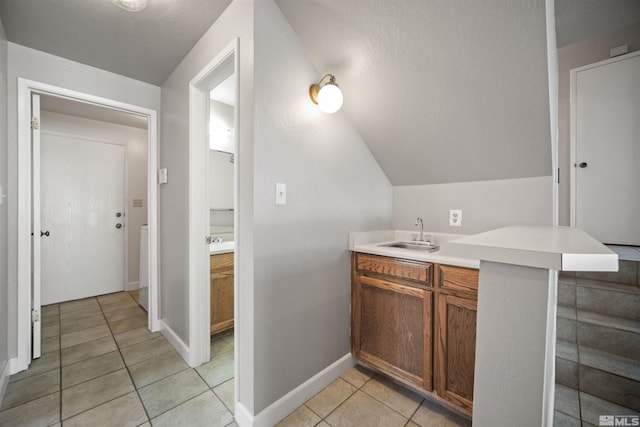 bathroom with tile patterned flooring, vanity, and vaulted ceiling