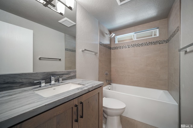 full bathroom with tile patterned floors, a textured ceiling, toilet, vanity, and tiled shower / bath