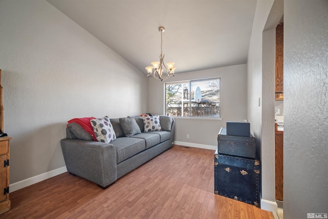 living room featuring a notable chandelier, wood-type flooring, and vaulted ceiling