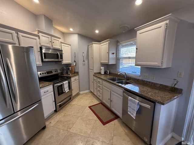 kitchen featuring sink, white cabinets, dark stone counters, light tile patterned flooring, and appliances with stainless steel finishes