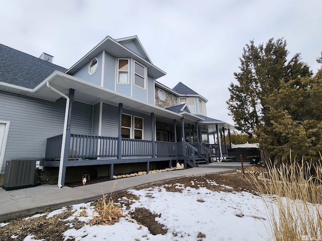 view of snowy exterior featuring cooling unit and covered porch