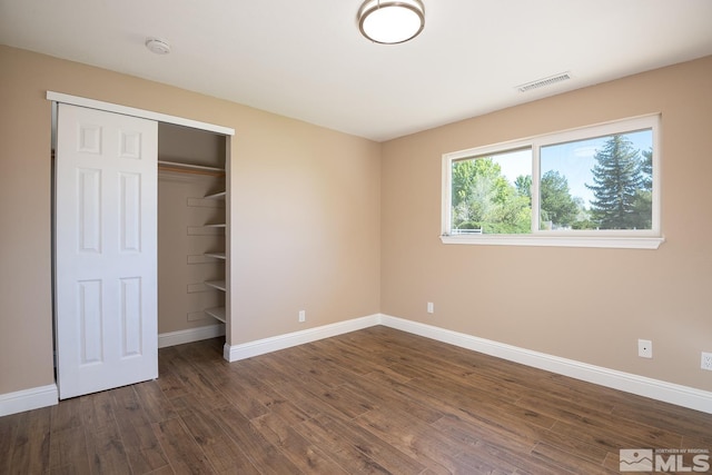 unfurnished bedroom with a closet and dark hardwood / wood-style flooring