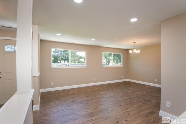 spare room featuring dark hardwood / wood-style flooring and an inviting chandelier