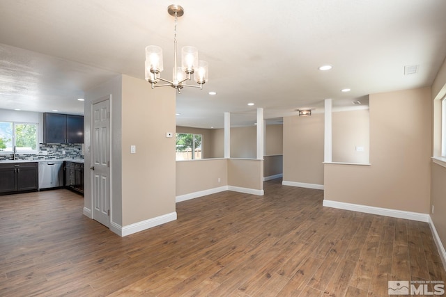 unfurnished room featuring a wealth of natural light, dark hardwood / wood-style flooring, a chandelier, and sink