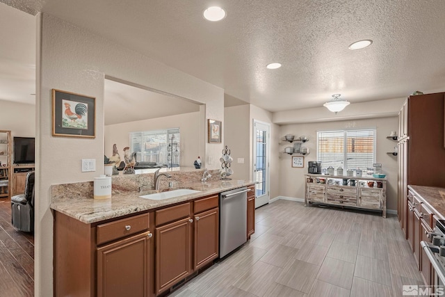 kitchen with light stone countertops, a textured ceiling, sink, dishwasher, and range