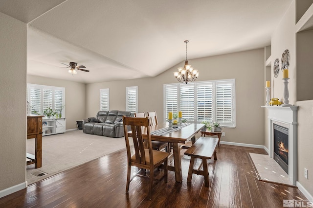 dining area with dark hardwood / wood-style flooring, ceiling fan with notable chandelier, and vaulted ceiling