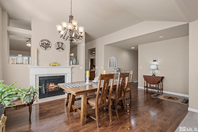 dining room with ceiling fan with notable chandelier, dark wood-type flooring, and lofted ceiling