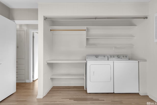 clothes washing area featuring light hardwood / wood-style floors and washing machine and clothes dryer