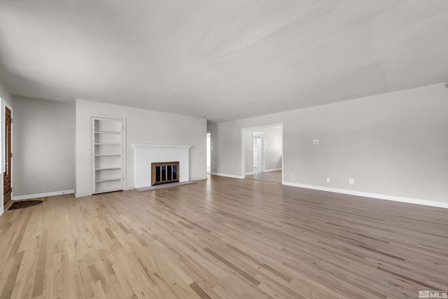 unfurnished living room with light wood-type flooring and built in features