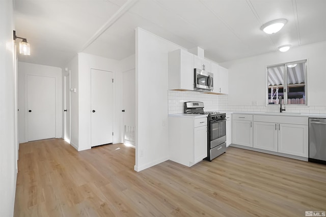 kitchen with decorative backsplash, stainless steel appliances, sink, white cabinets, and light hardwood / wood-style floors