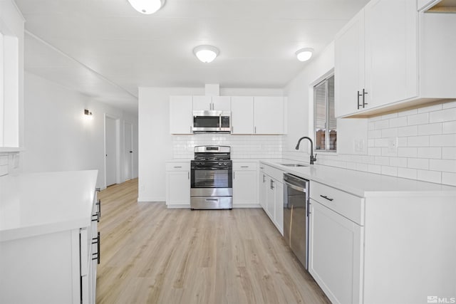 kitchen with white cabinetry, sink, appliances with stainless steel finishes, and light hardwood / wood-style flooring