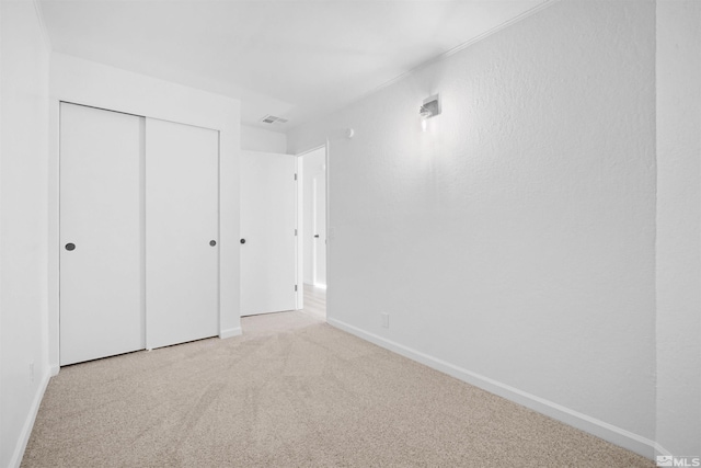 unfurnished bedroom with light carpet and a closet