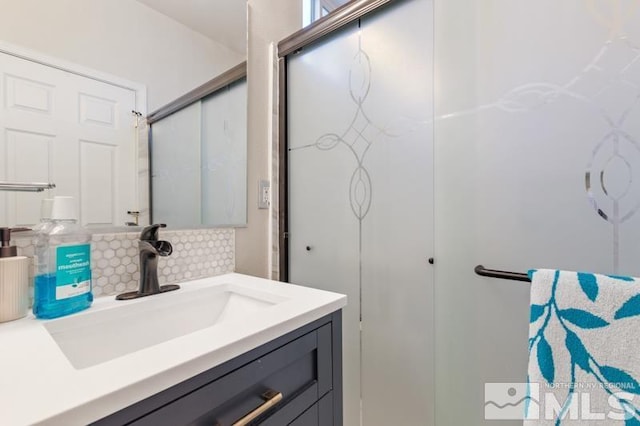 bathroom with decorative backsplash, vanity, and an enclosed shower