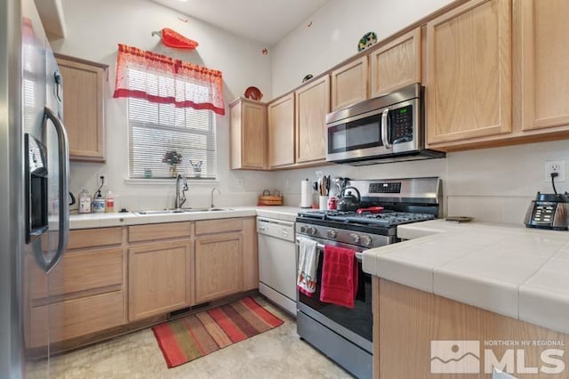 kitchen with tile counters, light brown cabinets, sink, and appliances with stainless steel finishes