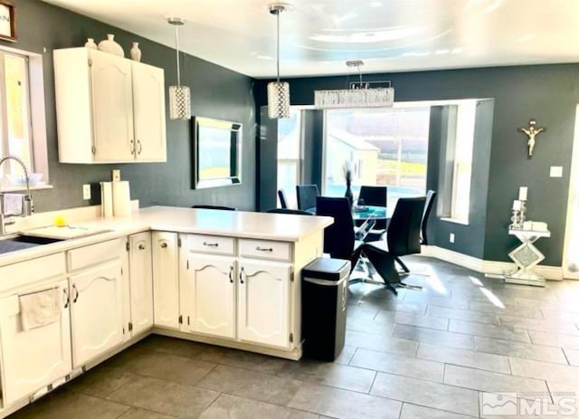 kitchen featuring pendant lighting, white cabinets, kitchen peninsula, and sink